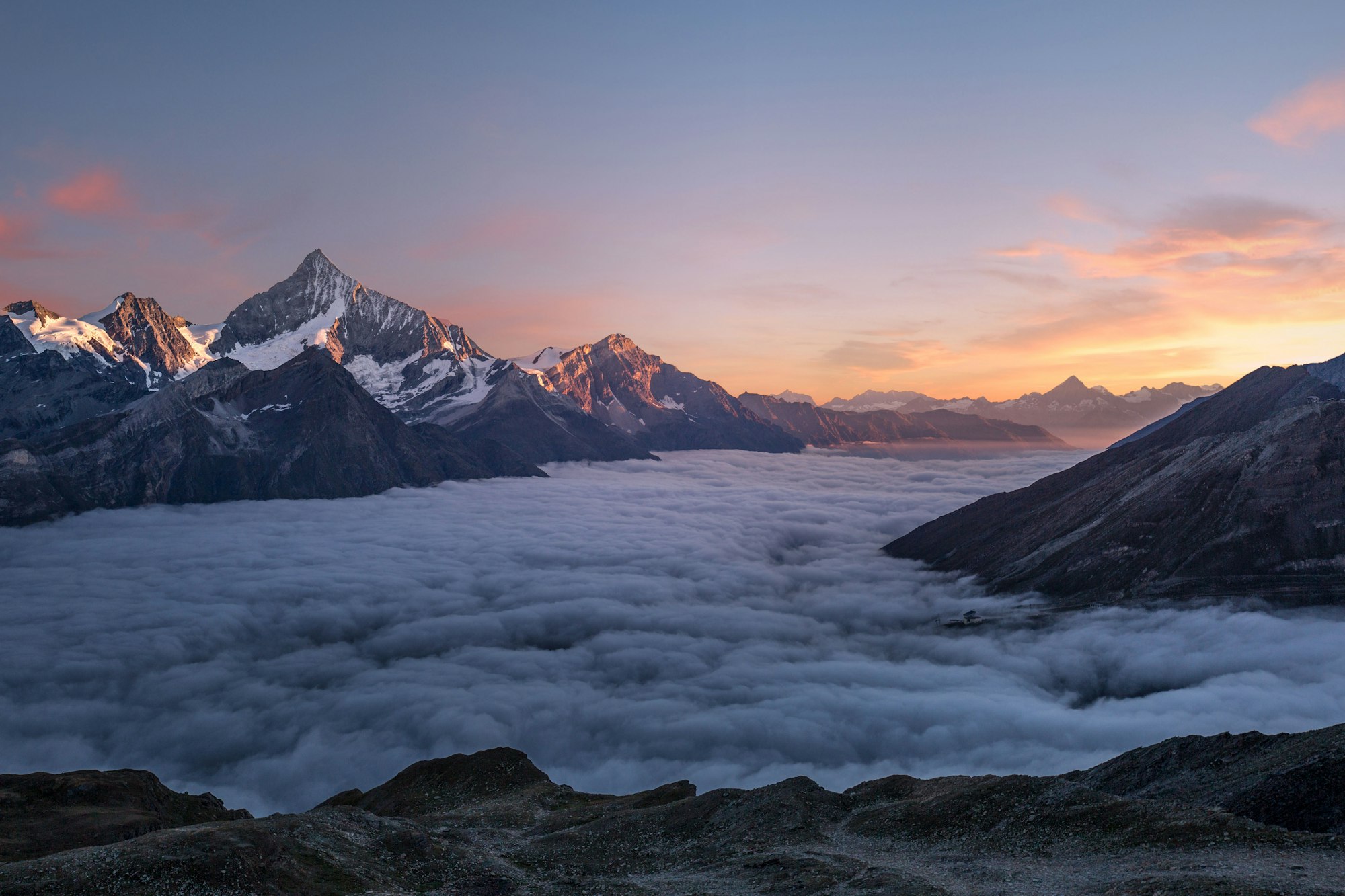 Sea of clouds over mountain peaks at dawn